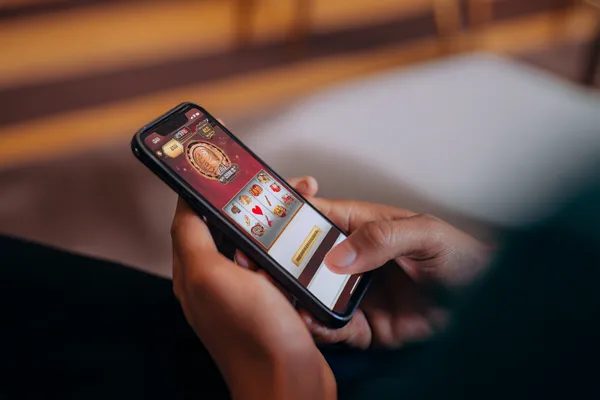 A cheerful woman in traditional clothing using her smartphone during a festive moment, showing how easily the 1XBEF app fits into everyday life.